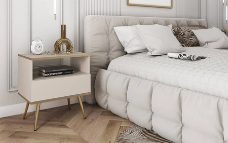 Luxusní béžový noční stolek se zásuvkou elegantní design skříňka doplněná zlatým lemováním skříňka stojí na vysokých kovových nožkách