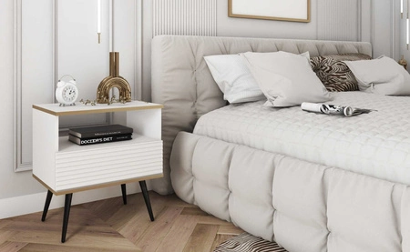 Luxusní bílý noční stolek se zásuvkou elegantní design skříňka se zlatým lemováním skříňka s rýhovaným čelem černé vysoké nohy